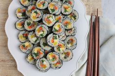 a plate full of sushi and chopsticks on a table