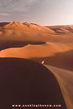 a person standing on top of a sand dune