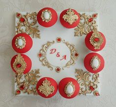 there are twelve red and gold decorated cupcakes on this square cake with white frosting