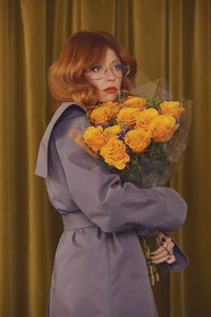 a woman with red hair and glasses holding flowers