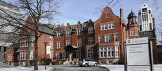 an old brick building with cars parked on the street and snow covered ground in front