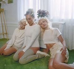 three women are sitting on the floor in front of a window and posing for a photo