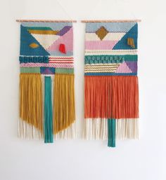 two woven wall hangings with tassels on them