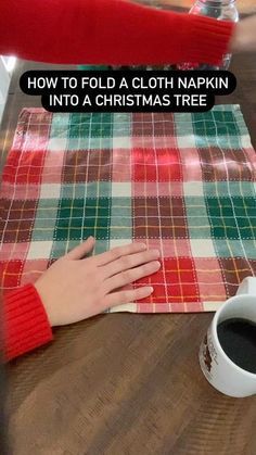 a woman is sitting at a table with her hand on a plaid cloth next to a cup of coffee