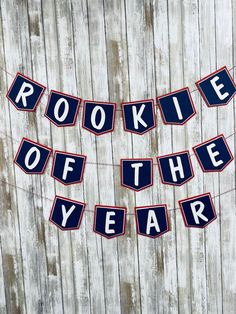 a banner that says rookie of the year hanging on a wooden fence with red, white and blue letters