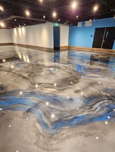 an empty room with blue and white paint on the floor, lights in the ceiling