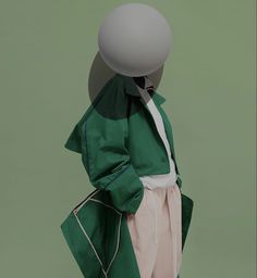 a person in a green jacket and white pants with a gray ball on their head