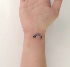 a person's hand with a small tattoo on the wrist that has a curved design