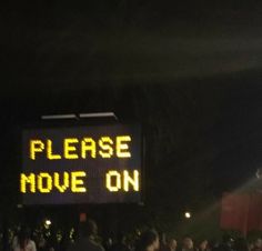 a sign that says please move on in front of a group of people at night