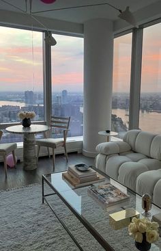 a living room filled with furniture and large windows overlooking the cityscape at sunset