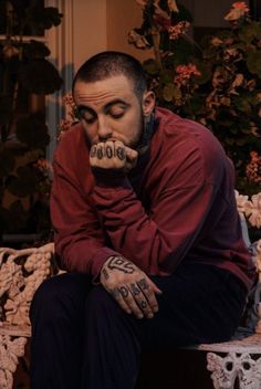 a man with tattoos on his hands sitting down