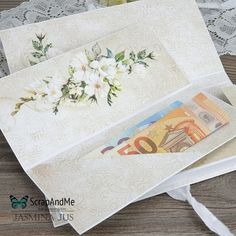 two cards with flowers on them sitting next to each other and some paper money in front of them