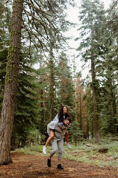 a man carrying a woman in the woods on his back while she is holding him