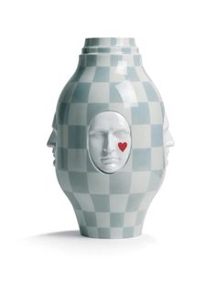 a ceramic vase with a face and a red heart on the side, sitting in front of a white background