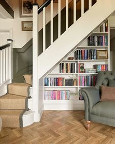 a chair sitting in front of a bookshelf filled with books next to a stair case