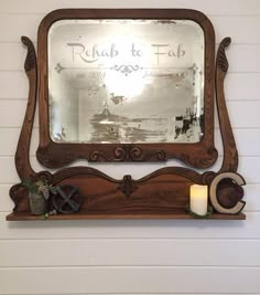 a mirror sitting on top of a wooden shelf next to a candle and potted plant