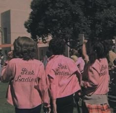 two girls in pink shirts are walking down the street with their hands up to the sky