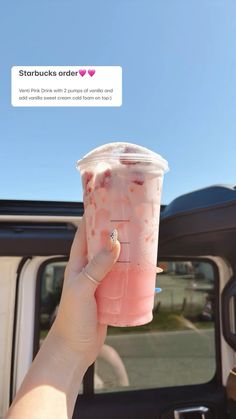 a person holding up a pink drink in their hand