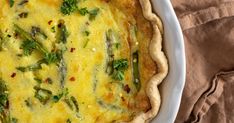 a quiche with asparagus and parsley in a white dish on a brown cloth