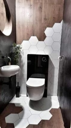 a white toilet sitting inside of a bathroom next to a sink and mirror on the wall