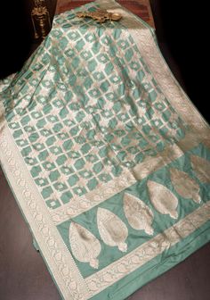 Elevate your ethnic collection with our Green Cyan Banarasi Katan Silk Saree, a stunning blend of tradition and elegance. This exquisite saree features intricate zari checks that create a striking visual effect, complemented by delicate Alfi buttas that add a touch of sophistication and artistry.  The green cyan hue brings a refreshing pop of color, making it perfect for festive occasions, weddings, or special celebrations. Crafted from Katan silk, this saree drapes beautifully, ensuring a graceful silhouette and all-day comfort. Pair it with traditional jewelry for a look that radiates charm and elegance, celebrating the rich heritage of Banarasi craftsmanship. Embrace the beauty of this exquisite piece and make a lasting impression! SILK MARK CERTIFIED This saree is ready to wear with fa Festive Pista Green Banarasi Silk Pre-draped Saree, Pista Green Banarasi Silk Pre-draped Saree For Eid, Pista Green Traditional Wear With Zari Work In Jamawar, Pista Green Meenakari Chanderi Saree, Pista Green Meenakari Chanderi Dupatta, Banarasi Silk Meenakari Dupatta In Pista Green, Green Banarasi Silk Dupatta With Meenakari, Pista Green Banarasi Silk Dupatta With Meenakari, Pista Green Art Silk Dupatta For Eid