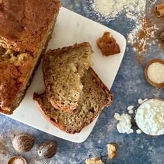 a loaf of bread sitting on top of a cutting board next to nuts and butter