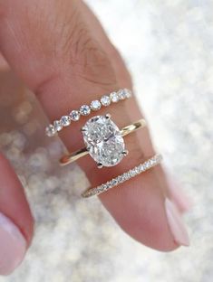 a woman's hand with three rings on her fingers and one ring in the middle