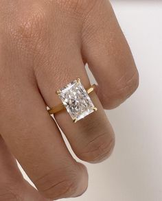 a woman's hand with a diamond ring on top of her finger, showing the center stone