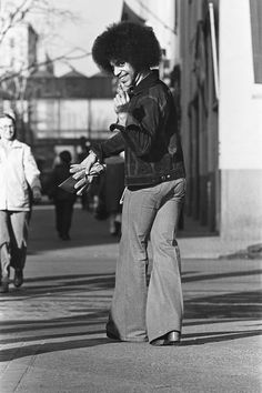 an old photo of a woman walking down the street with her hand in her mouth