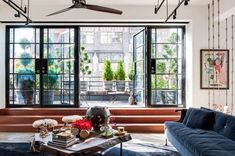 a living room with blue couches and large windows in the back ground floor area