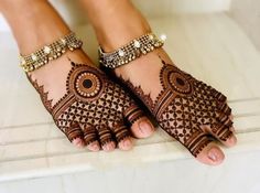 two feet with henna tattoos on them, one is wearing gold jewelry and the other has