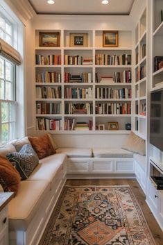 a living room filled with lots of books on top of a white book shelf next to a window