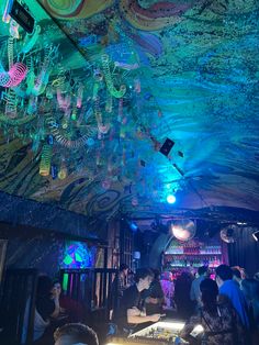 people are sitting at tables in a brightly lit room with chandeliers hanging from the ceiling