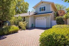 a house with a driveway in front of it and lots of bushes around the yard