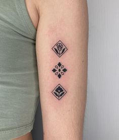 a woman with a tattoo on her arm showing the cross and three diamonds in black ink