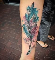 a woman's leg with a colorful feather tattoo on it