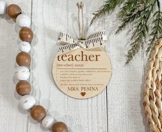 a wooden teacher ornament hanging on a wall next to a basket and pine tree