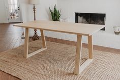 a wooden table sitting on top of a rug next to a fireplace