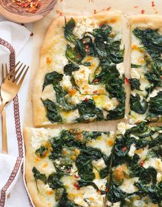 a pizza with spinach and cheese cut into squares