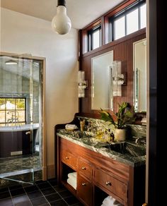 a bathroom with two sinks and a large mirror above the sink in front of a walk in shower