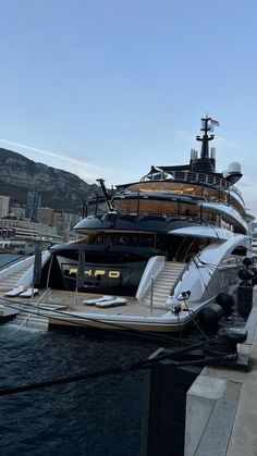 a large boat docked in the water near a dock with other boats and yachts