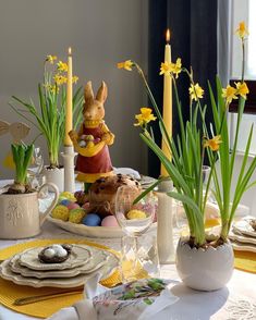 an easter table setting with yellow flowers and candles