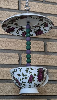 two hanging bowls with flowers on them are attached to a chain by a brick wall