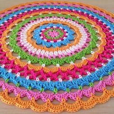 a crocheted doily is shown on a wooden surface with multicolored circles