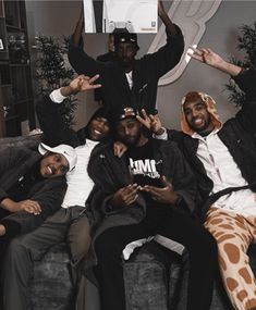 four men sitting on a couch posing for the camera with their arms in the air