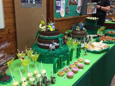 a green table topped with lots of cakes and desserts