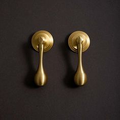 two golden door handles on a black surface