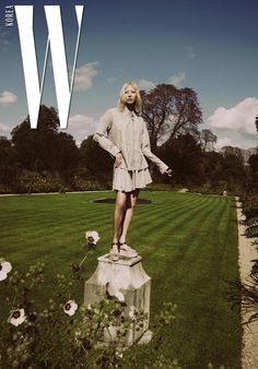 a woman standing on top of a statue in the grass