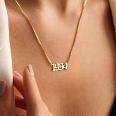 a woman wearing a gold necklace with the word mom on it