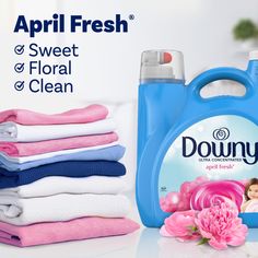 a bottle of downy fabric fresh next to some folded towels and pink carnations